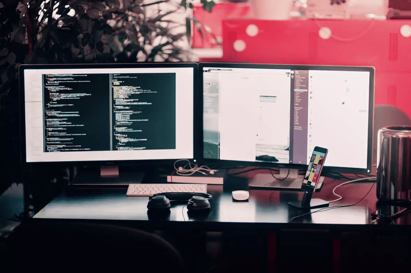 two computer monitor one smartphone one earphone on a table